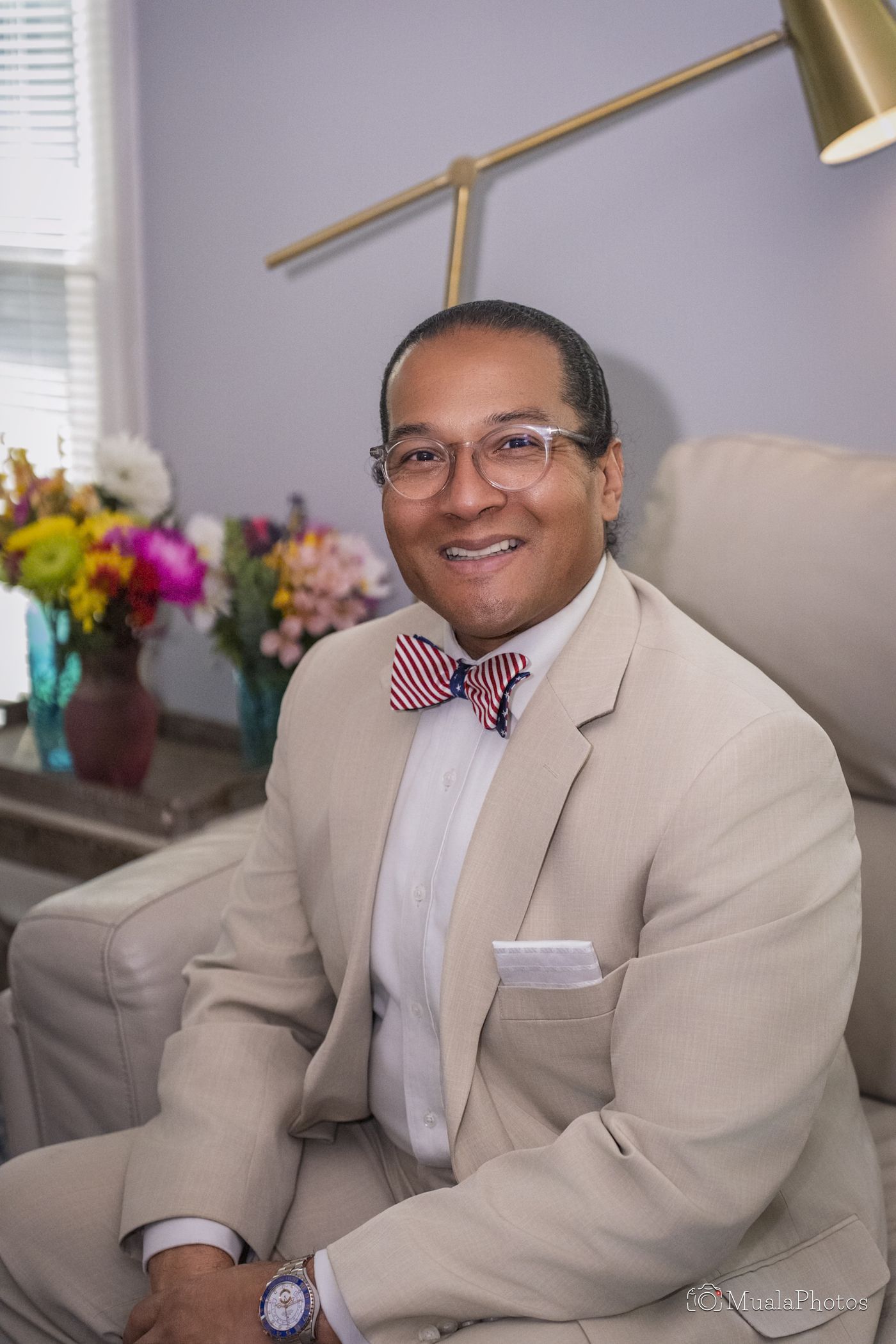 Dr. James M. Thompson I seated and smiling, in a tan suit with a patriotic bow tie